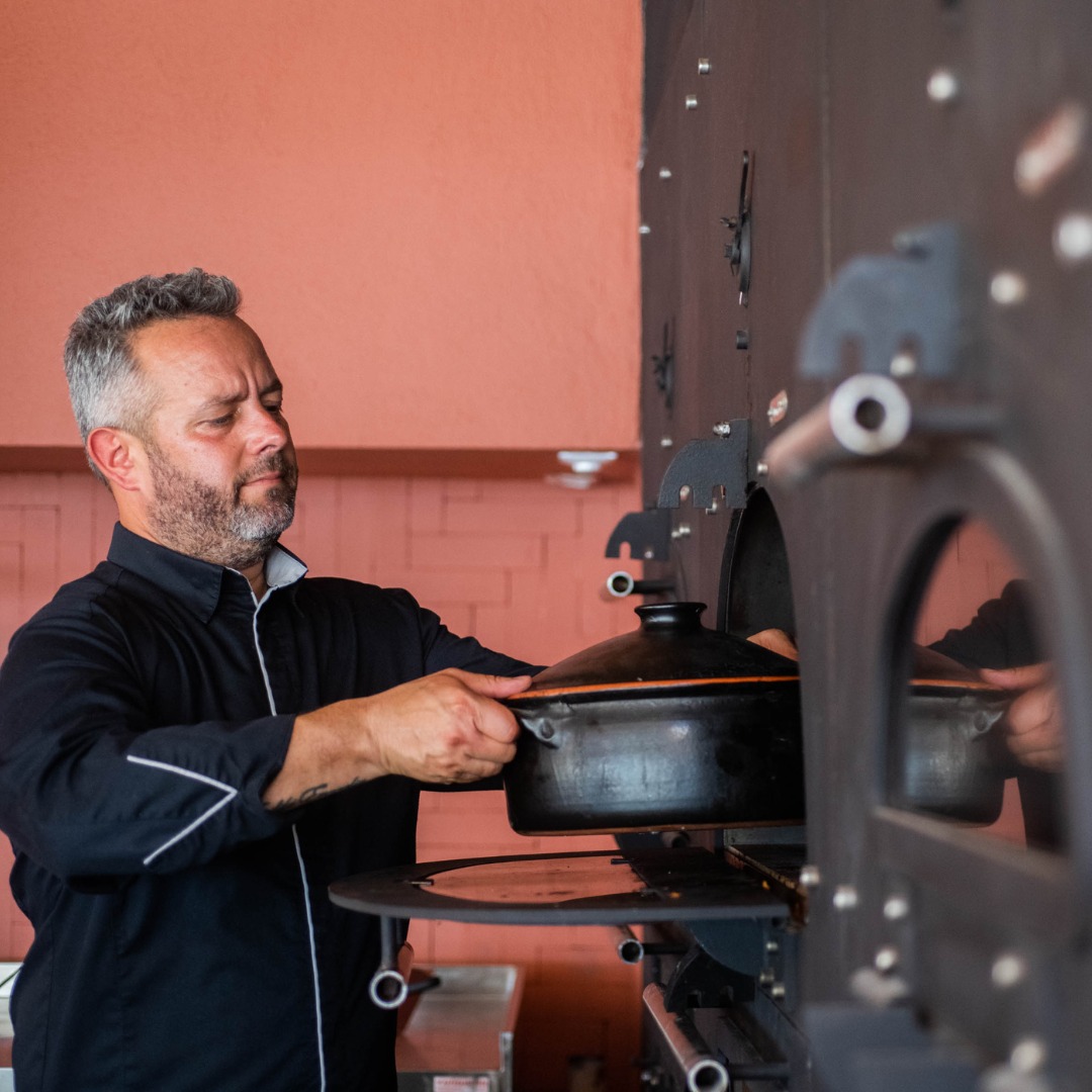 Chef Giannis Parikos placing octopus into the wood-fired oven at SeaRocks Paros